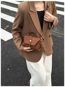 Detail einer dunkelbraunen Vintage-Handtasche mit Goldschnalle, präsentiert auf der Straße