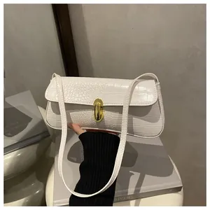 Detail of white crocodile embossed underarm bag with elegant gold twist lock closure