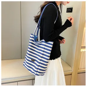 Detail of blue and white striped canvas tote bag with a leather handmade label