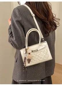 Detail of white leather crossbody bag with floral embroidery and ice cream charm