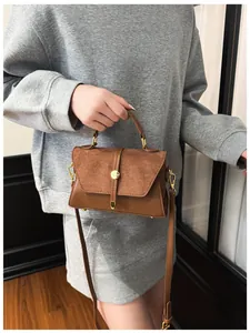 Detail einer braunen Leder- und Wildledertasche mit Goldschnalle am Modell