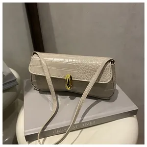 Detail of a creamy white crocodile texture bag featuring a glossy gold capsule metal lock