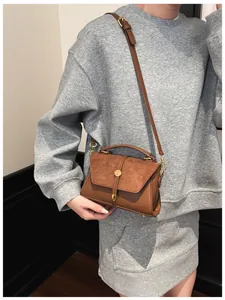 Detail der braunen Vintage-Handtasche aus Wildleder mit Goldschnalle und Schultergurt