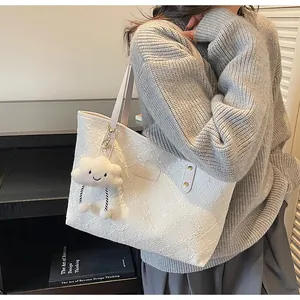 Detalle del bolso tote blanco con grabado floral y colgante de nube de felpa suave
