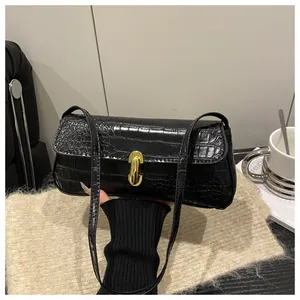 Close-up of black croc-embossed shoulder bag featuring a gold twist lock and fine texture