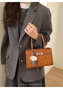 Detailed view of a brown leather bag with GA crown embroidery and an ice cream bag charm
