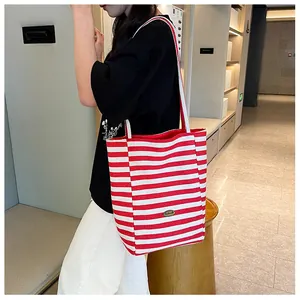Detail of red and white striped canvas tote bag showing the side view and shoulder straps