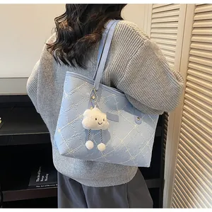 Detalle del bolso tote bordado azul claro con un lindo colgante de nube de peluche