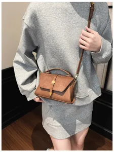 Braune Damenhandtasche mit Schultergurt, getragen von einem Model im Freizeit-Look