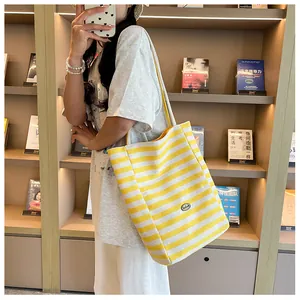 Close-up of a large yellow and white striped canvas tote bag with a wide shoulder strap