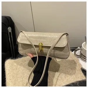 Close-up of beige crocodile pattern handbag with gold metal lock in a lifestyle setting