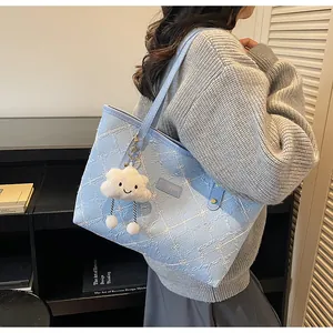 Detalle del bolso tote azul claro con bordado floral blanco y colgante de nube de peluche