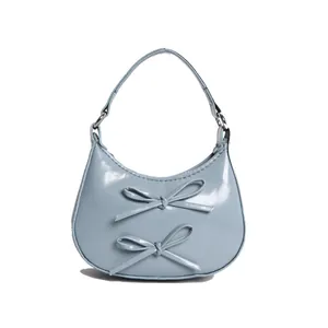 Elegant light blue glossy patent leather handbag with bow accents and silver rings