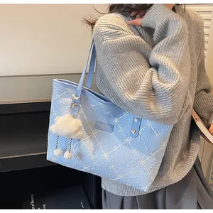 Detalle del bolso tote azul claro con bordado de lazos y un colgante de nube suave