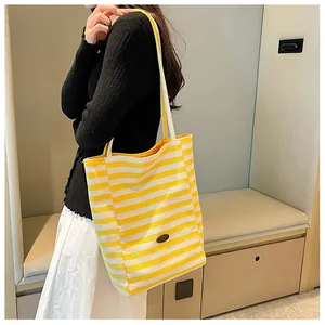 Side view of a striped canvas tote bag with long shoulder straps and yellow inner lining