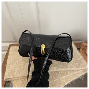 Detailed view of black crocodile pattern faux leather and golden metal clasp on shoulder bag