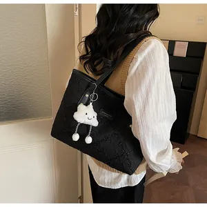 Detalle del bolso tote acolchado negro con un lindo colgante de peluche de nube blanca