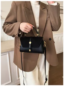 Details einer schwarzen Lederhandtasche mit goldener Schließe und strukturierter Klappe