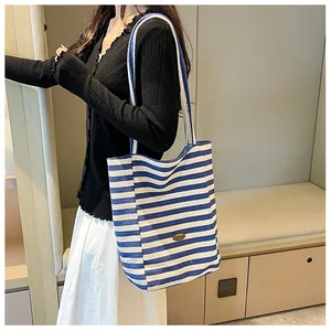 Detail of blue and white striped canvas tote bag with brown leather brand tag