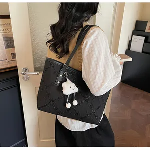 Detalle de bolso shopper negro acolchado con colgante de nube blanca y correas de hombro