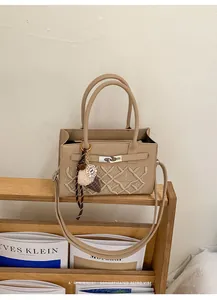 Detail view of beige crossbody bag featuring geometric embroidery and metal buckle closure