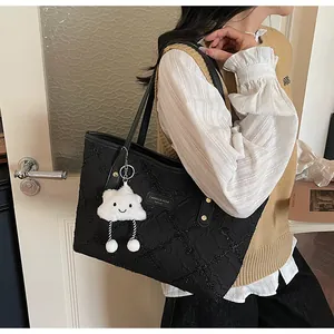 Detalle del bolso tote acolchado negro con colgante de nube blanca y asas de cuero