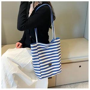 Detailed view of the thick blue and white striped canvas tote bag with oval logo plate