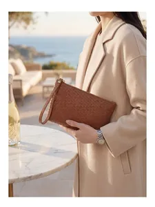 Detail of woven caramel leather clutch showing intricate texture and wrist strap