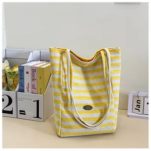 Detail of yellow and white striped canvas tote bag with handmade leather patch