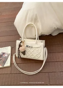 Detail of white leather bag with geometric floral embroidery and silver metal clasp