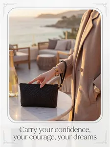 Close-up of black woven leather clutch with gold zipper and wristlet strap detail