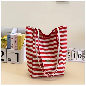 Detail of red and white striped canvas tote bag with a vintage metal logo on top