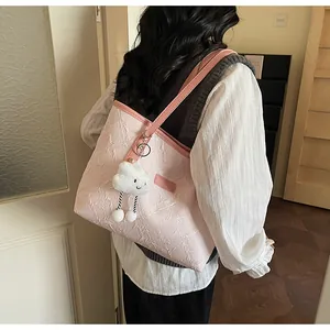 Detalle del bolso tote rosa con relieve floral y un lindo colgante de nube suave