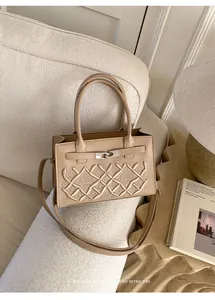 Detail of retro beige crossbody bag with diamond stitch pattern and silver metal swivel lock