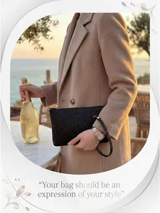 Detail of a black woven leather clutch bag with wristlet in an elegant outdoor setting