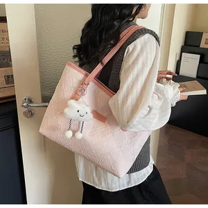 Detalle del bolso tote rosa claro con textura floral en relieve y colgante de nube