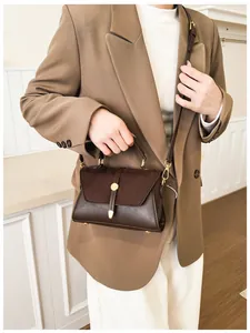 Details einer braunen Vintage-Handtasche mit goldener Schnalle und Gurt am Modell