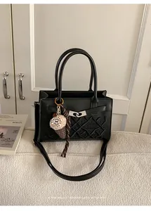 Detailed view of black crossbody bag with diamond quilting and plush ice cream charm