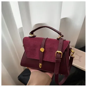 Detailaufnahme der burgunderroten Leder- und Wildlederkontraststrukturen der Handtasche