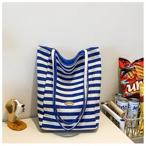 Detail of blue striped canvas tote bag featuring an oval handmade leather patch