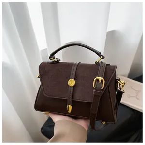 Detail der dunkelbraunen Lederhandtasche mit Wildlederklappe und goldener Schnalle