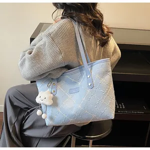 Detalle de bolso tote azul claro con bordado floral en 3D y colgante de nube suave