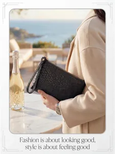 Close-up of black woven leather clutch bag with wrist strap in a coastal setting