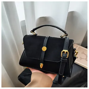 Detail der schwarzen Handtasche mit Wildleder-Glattleder-Mix und goldener Schnalle