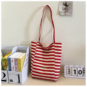 Close-up of red and white striped canvas tote with oval vintage metal emblem detail