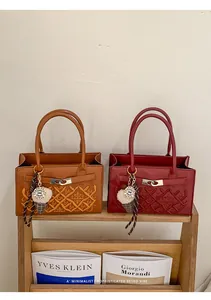 Macro detail of monogrammed leather bags with vintage metal clasp and plush ice cream charm