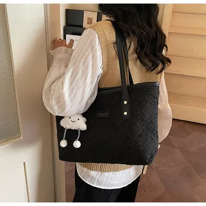 Detalle de bolso tote acolchado negro con asas de cuero y colgante de nube blanca suave