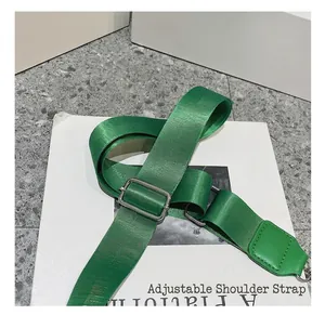 Detail view of the adjustable green nylon shoulder strap with silver metal buckles