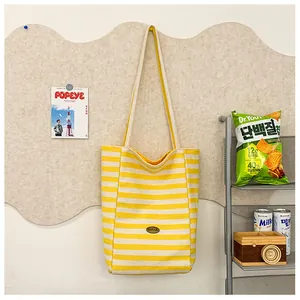 Detail of yellow and white striped canvas tote bag hanging on a cork board