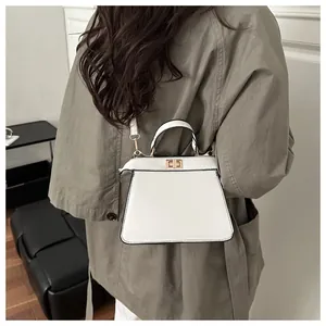Detailansicht einer weißen Trapez-Handtasche mit Goldschließe und Trenchcoat-Look
